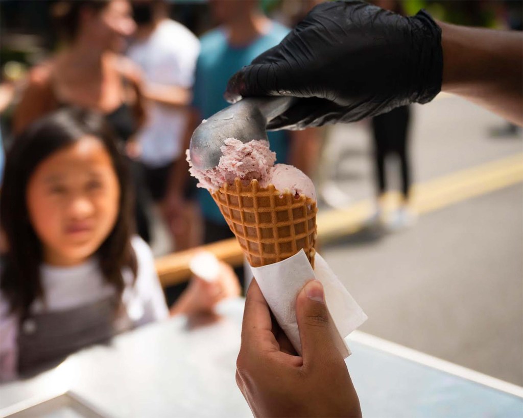 A young customer watches the assembly of a strawberry ice cream cone.